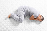 Mature man sleeping on soft mattress, top view