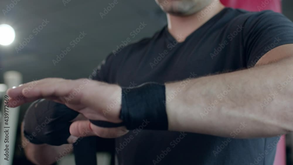 Man puts an elastic bandage around his wrist in the gym. Man puts an elastic bandage around his wrist in the gym.