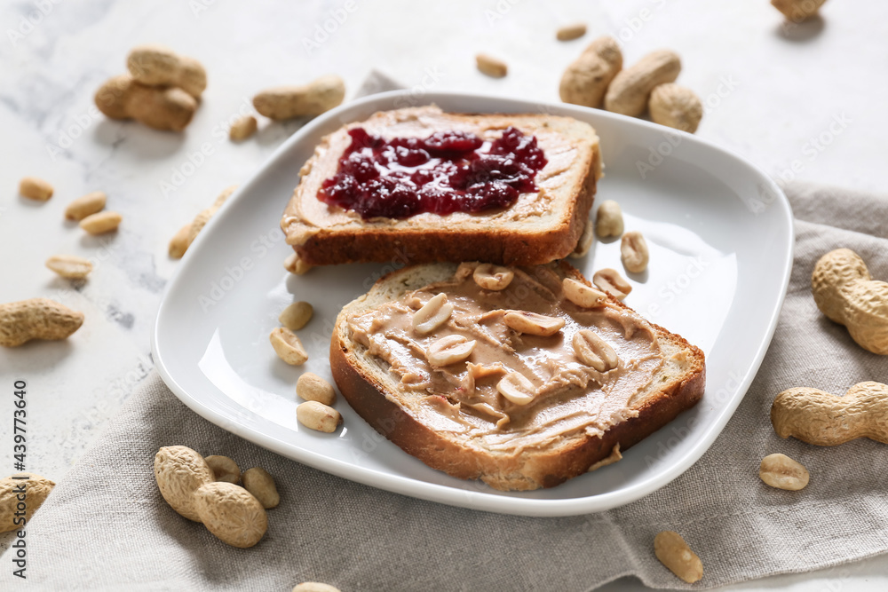 Plate with tasty bread, peanut butter and jam on table Plate with tasty bread, peanut butter and jam on table