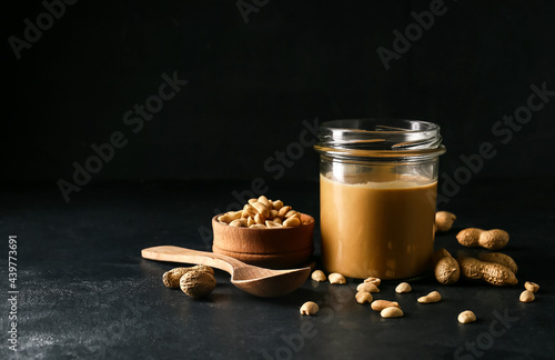 Fotografie Jar with tasty peanut butter on dark background