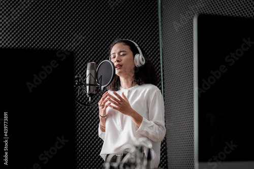 Asian female singer with a passion for music and microphone. While playing her guitar in a professional studio. Music concept, sound recording concept. photo