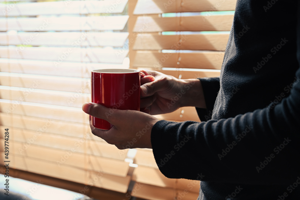 Man standing near window and holding coffee cup. Man standing near window and holding coffee cup.