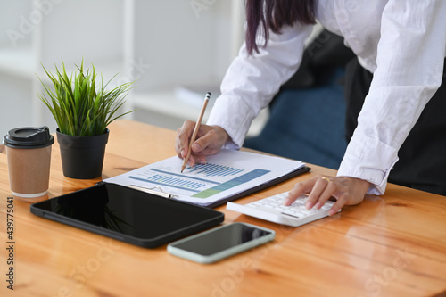 Accountant analysis data charts and using calculator on office desk.