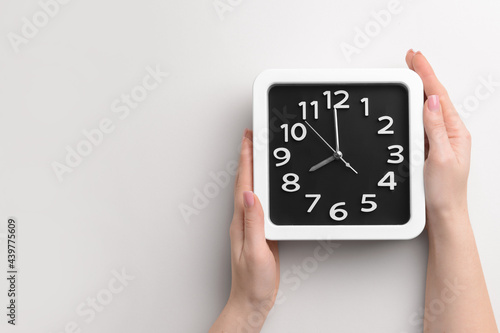 Female hands with stylish clock on light background, closeup