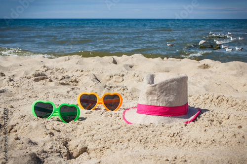 Sunglasses and straw hat on sand at beach. Sun protection while sunbathing. Travel and vacation time