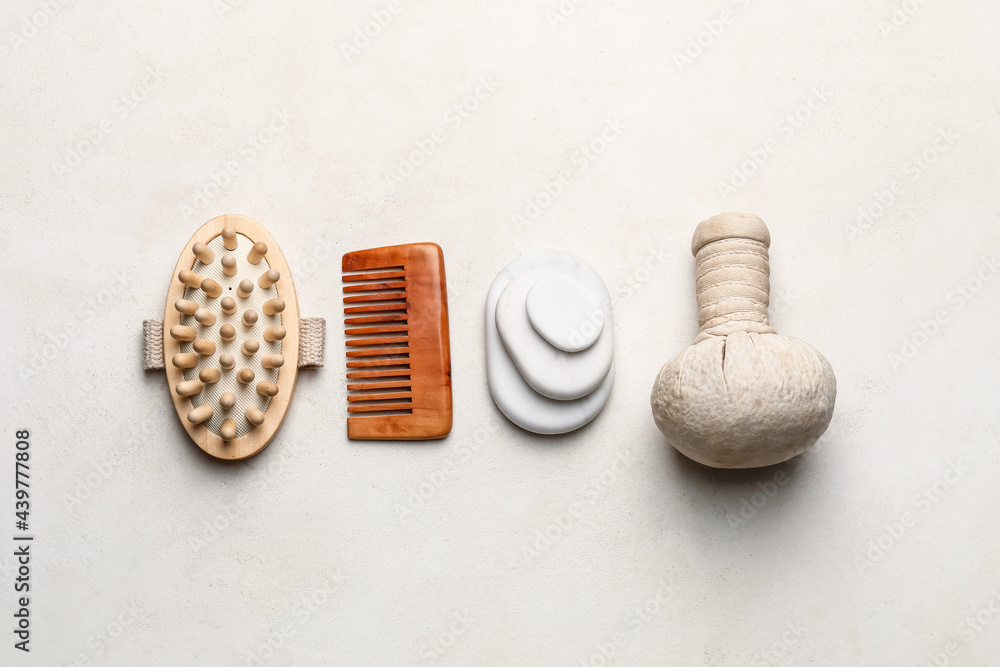 Fototapeta premium Wellness and spa tools for relaxation and self-care, including wooden massage brush, comb, hot stones, and herbal compress