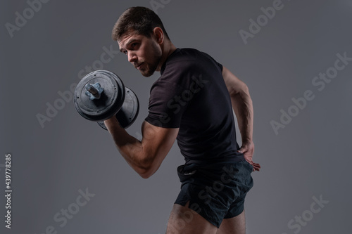 Cuadro en lienzo Focused strong guy performing bicep curls with dumbbell