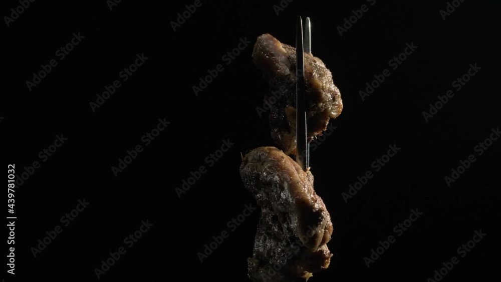 4k Fork with pieces of delicious barbecued meat on black background. Delicious pork pieces on rotating fork close-up. Grilled cubes of pork meat on fork. 4k Fork with pieces of delicious barbecued meat on black background. Delicious pork pieces on rotating fork close-up. Grilled cubes of pork meat on fork.
