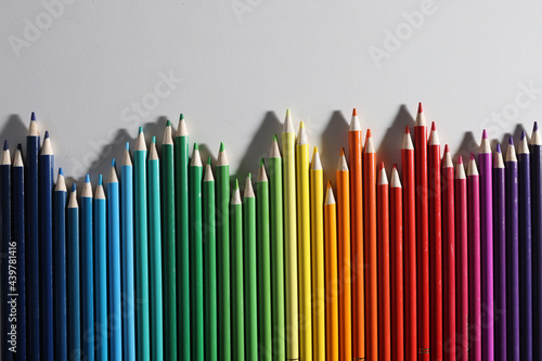 Colored pencils of different shades lie in row on white background