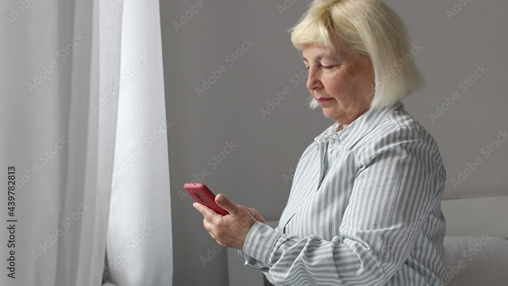 Caucasian 50 years old woman texting on mobile phone using wifi internet at home holding cell phone. 5G technology device. Caucasian 50 years old woman texting on mobile phone using wifi internet at home holding cell phone. 5G technology device.