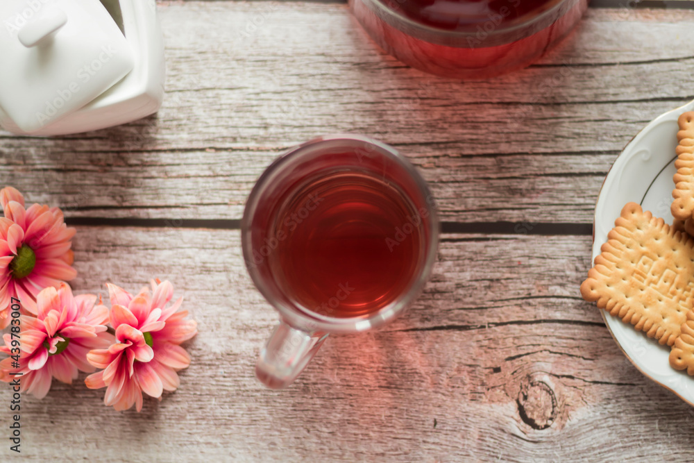 Morning tea is on the table. Flowers and biscuits lie nearby. Morning tea is on the table. Flowers and biscuits lie nearby.