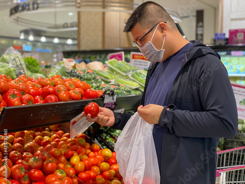 Asian man wearing medical face mask while shopping at grocery store