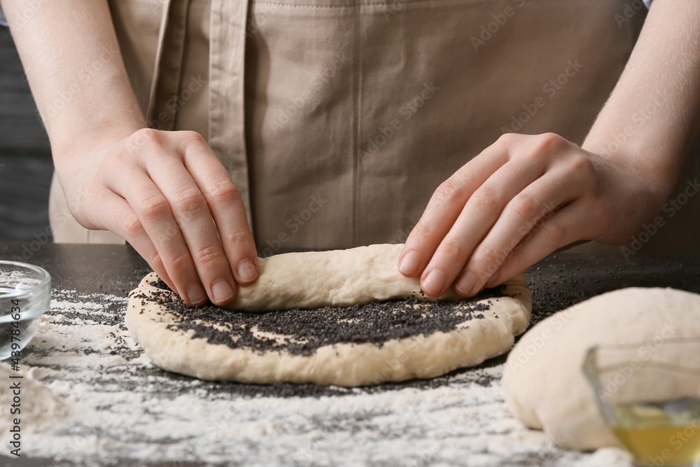 Female chef making delicious poppy seed bun on table, closeup Female chef making delicious poppy seed bun on table, closeup
