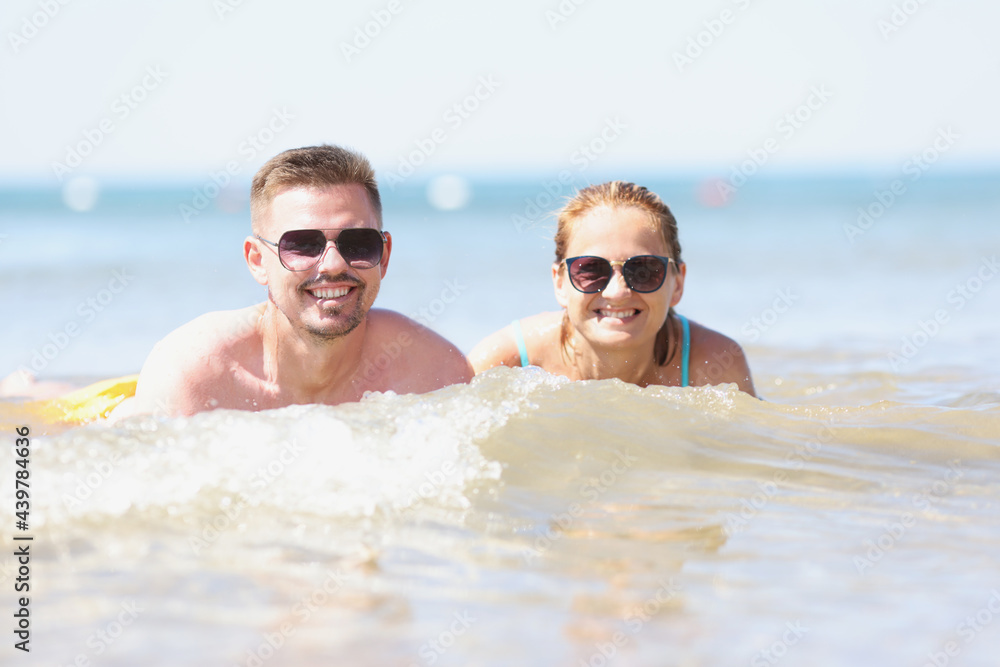 Young happy beautiful couple woman and man lying in sea water Young happy beautiful couple woman and man lying in sea water