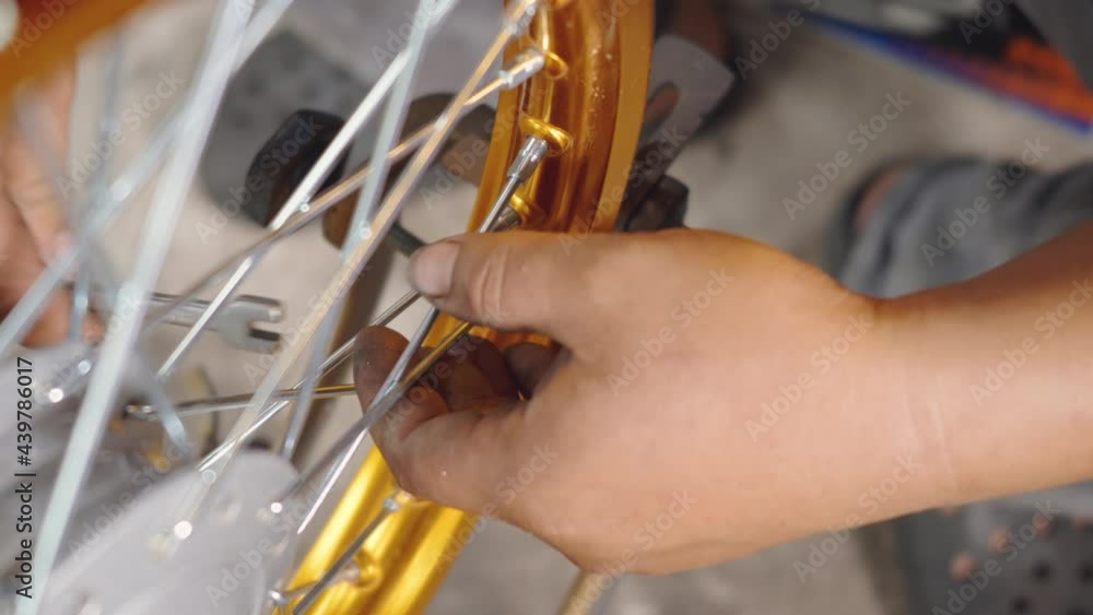 Technician man working motorcycle wheel has spokes weave up on mechanic