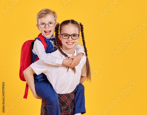 Obraz na plátne Happy schoolgirl giving piggyback ride to boy
