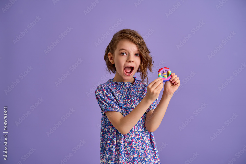 Teen age Girl in blue summer flower print dress holding pop it antistress toy on lavender background, isolate. Teen age Girl in blue summer flower print dress holding pop it antistress toy on lavender background, isolate.