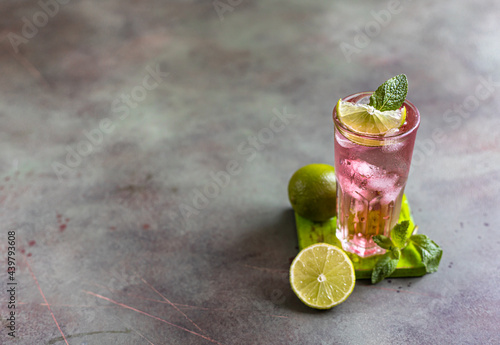 A fresh pink cocktail or mocktail drink with lime, pink grapefruit juice and mint, green background. Paloma.