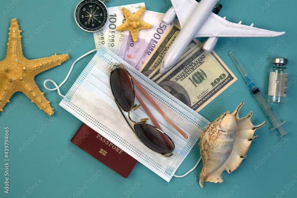airplane model, passport with medical mask covered, ampoule with vaccine and syringe, dollar and euro bills, sunglasses, starfish, seashell and compass airplane model, passport with medical mask covered, ampoule with vaccine and syringe, dollar and euro bills, sunglasses, starfish, seashell and compass