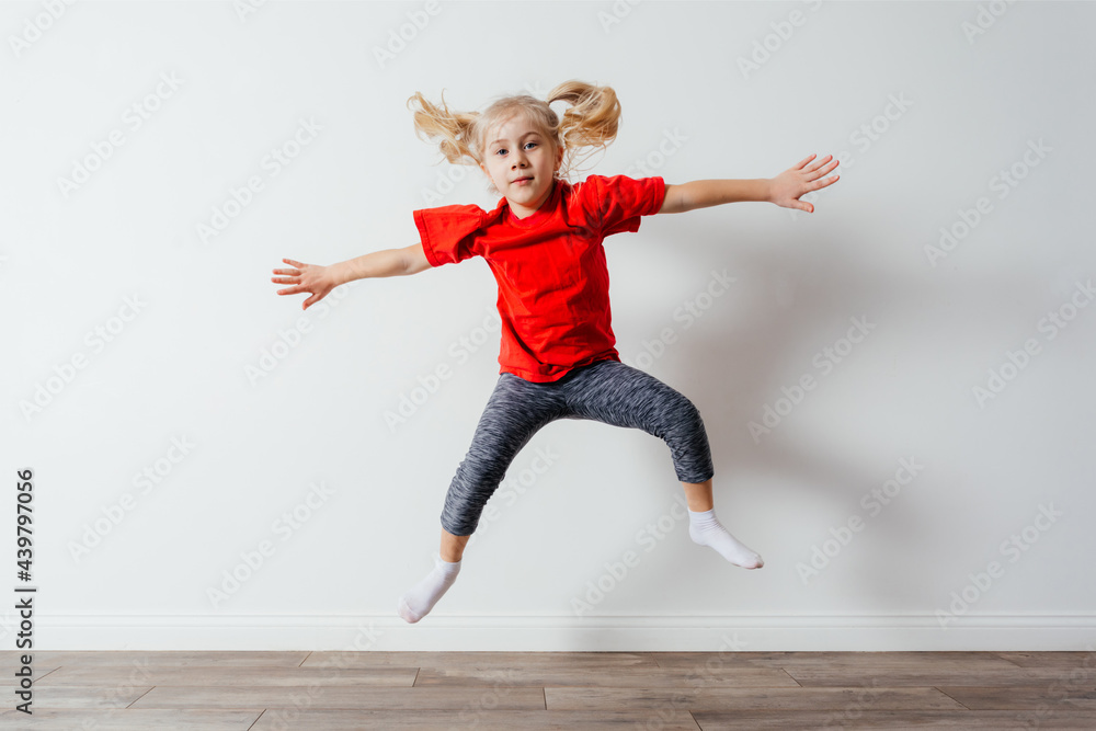 Happy jumping preschool girl in red t-shirt