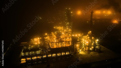 Flying along the oil refinery on a foggy night with bright night golden lighting