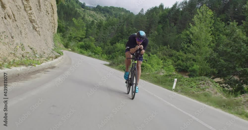 Triathlon sportsman athlete cyclist riding professional racing bicycle. Wearing black sportswear. Triathlon sportsman athlete cyclist riding professional racing bicycle. Wearing black sportswear.
