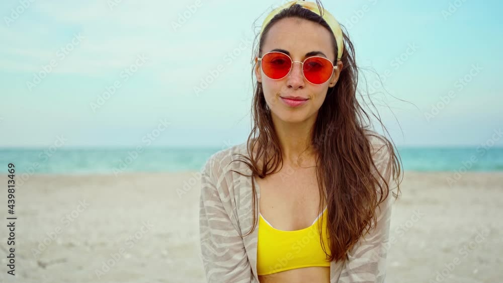 Close-up outdoors fashion portrait young woman wearing yellow bikini and pink sunglasses by sea on tropical beach Close-up outdoors fashion portrait young woman wearing yellow bikini and pink sunglasses by sea on tropical beach