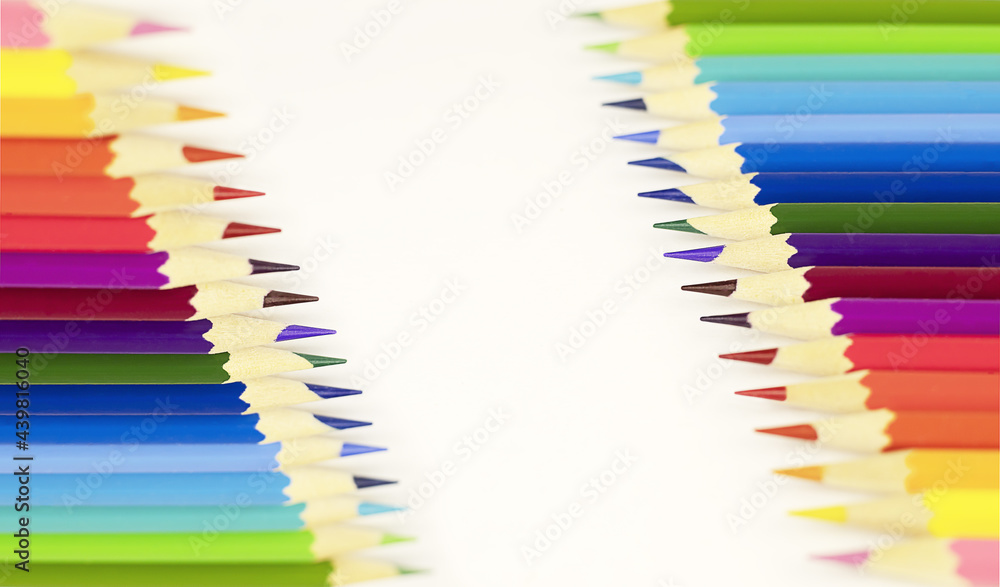 White background with colored pencils on both sides. Wooden colored pencils for drawing on paper, study concept. White background with colored pencils on both sides. Wooden colored pencils for drawing on paper, study concept.