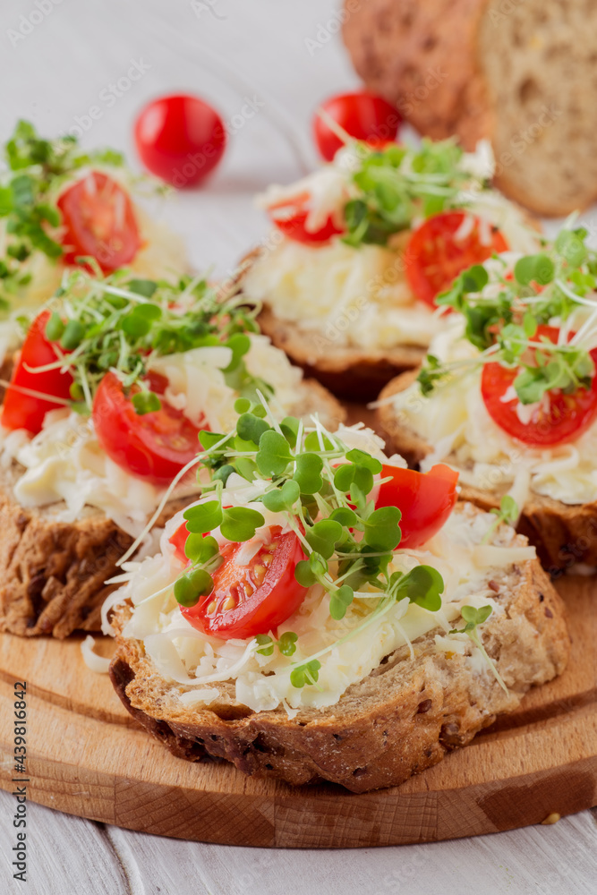 Bruschetta with tomatoes, cheese and microgreens on a board. Bruschetta with tomatoes, cheese and microgreens on a board.