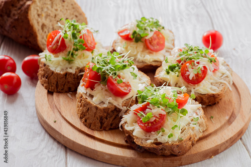 Bruschetta with tomatoes, cheese and microgreens on a board.