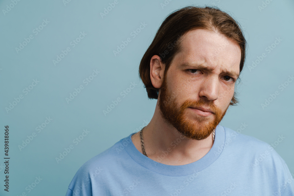 Young ginger man with beard frowning and looking at camera
