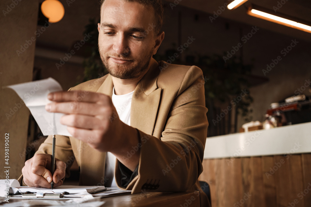 Young white man working with receipt while sitting at table in cafe Young white man working with receipt while sitting at table in cafe