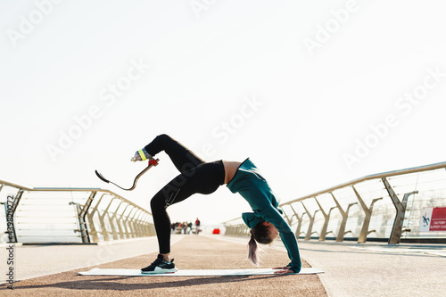 Young sportswoman with prosthesis doing exercise while working out