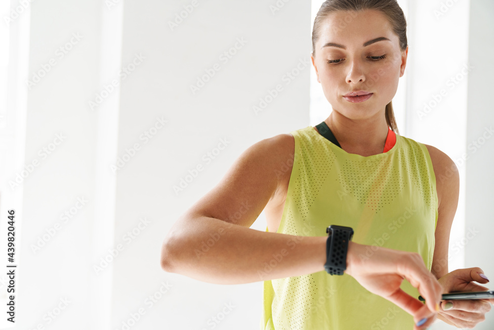 Young white sportswoman looking at her smartwatch during practice Young white sportswoman looking at her smartwatch during practice