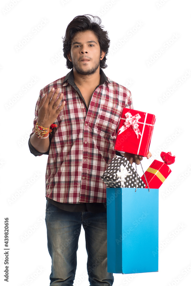 Young men showing rakhi on his hand with shopping bags and gift box on the occasion of Raksha Bandhan festival. Young men showing rakhi on his hand with shopping bags and gift box on the occasion of Raksha Bandhan festival.