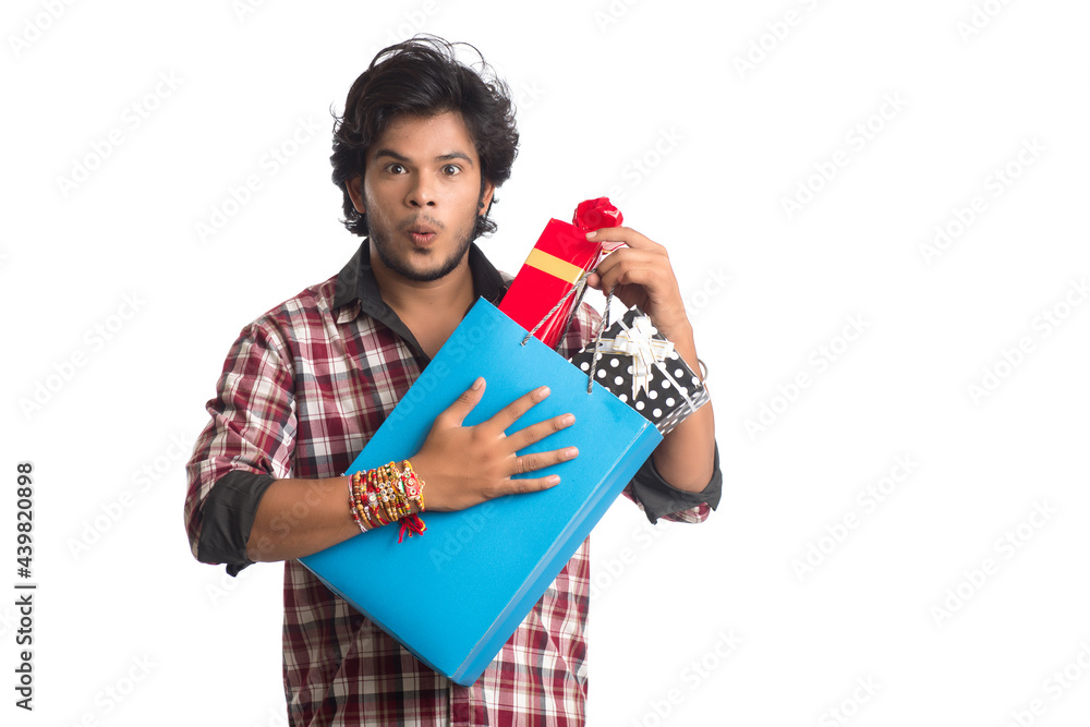 Young men showing rakhi on his hand with shopping bags and gift box on the occasion of Raksha Bandhan festival.