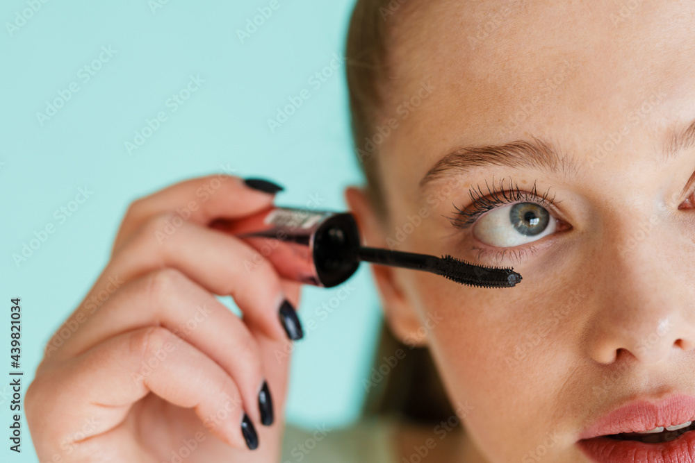 Young blonde woman applying mascara and looking upward Young blonde woman applying mascara and looking upward