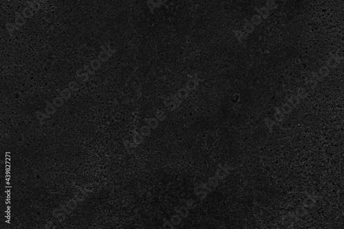 Black exposed aggregate concrete texture. Dark rough cement with pebble slab surface. Gloomy abstract grunge background