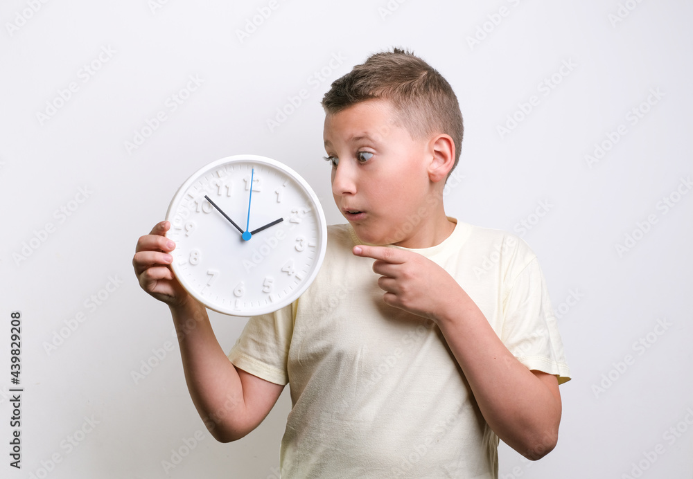 Shocked funny boy holding white clock alarm, copy space. Kid isolated over white background. Schedule and timing concept. Shocked funny boy holding white clock alarm, copy space. Kid isolated over white background. Schedule and timing concept.