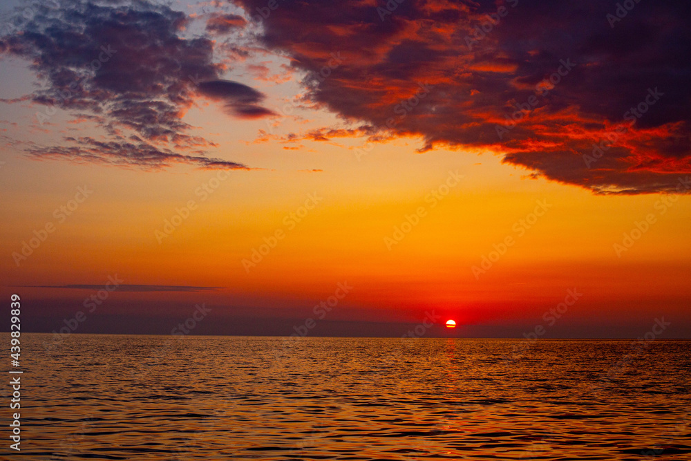 fiery sunset on the sea round sun goes beyond the horizon