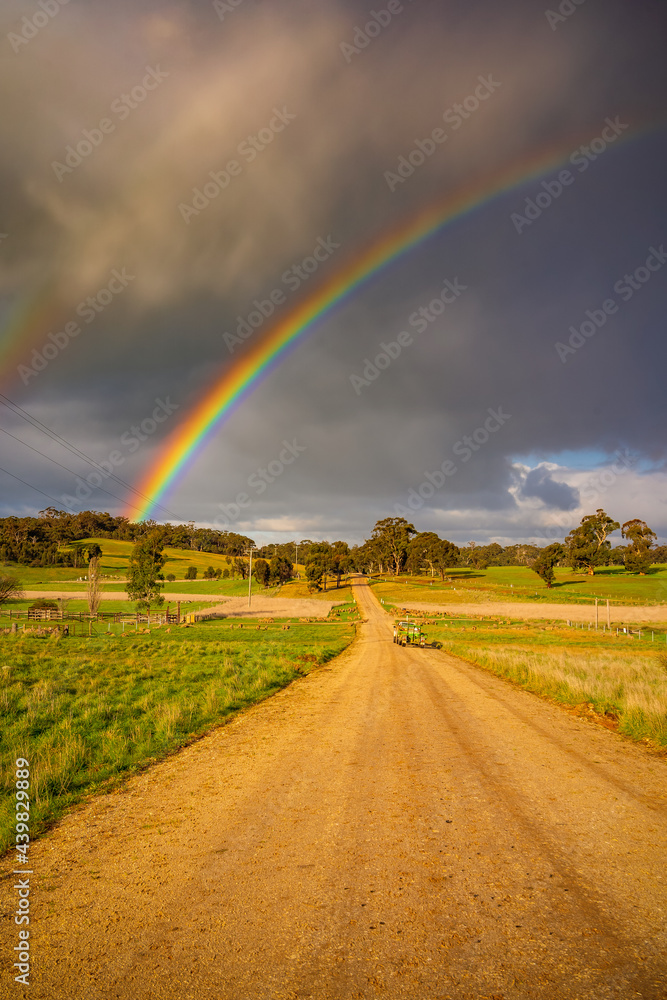 A rainbow in a dark sky over a country road A rainbow in a dark sky over a country road