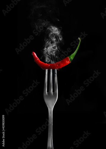 Fresh raw red hot chilli pepper on fork on Black Background