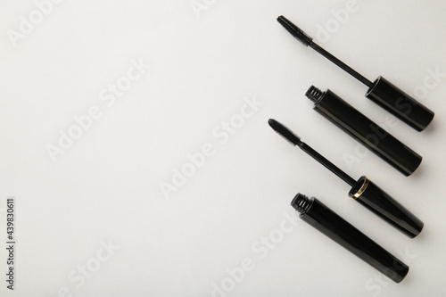 Black mascara wand and tube on grey background with copy space