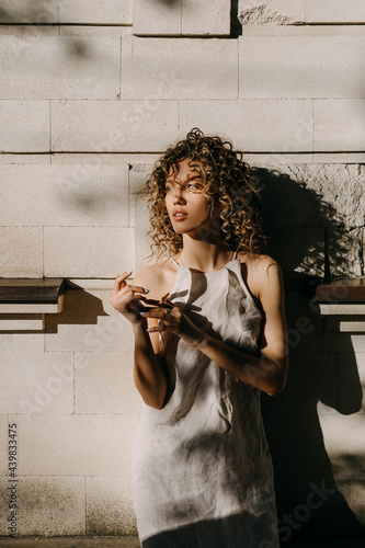 Canvas Print Young woman in harsh light, posing on a city building wall background