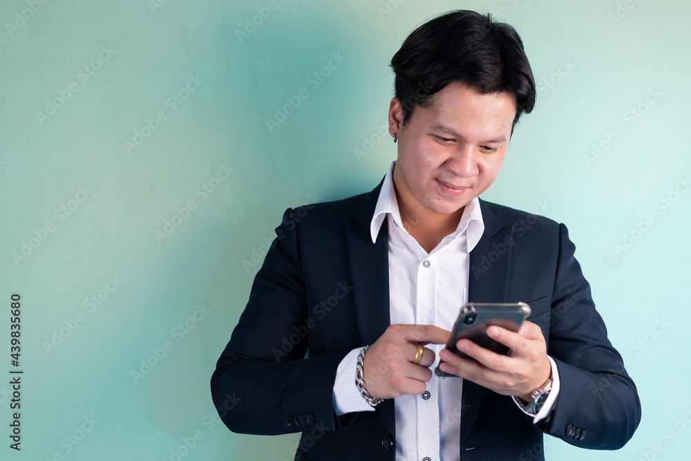 Handsome businessman wearing suit and using mobile phone on aqua background. Handsome businessman wearing suit and using mobile phone on aqua background.