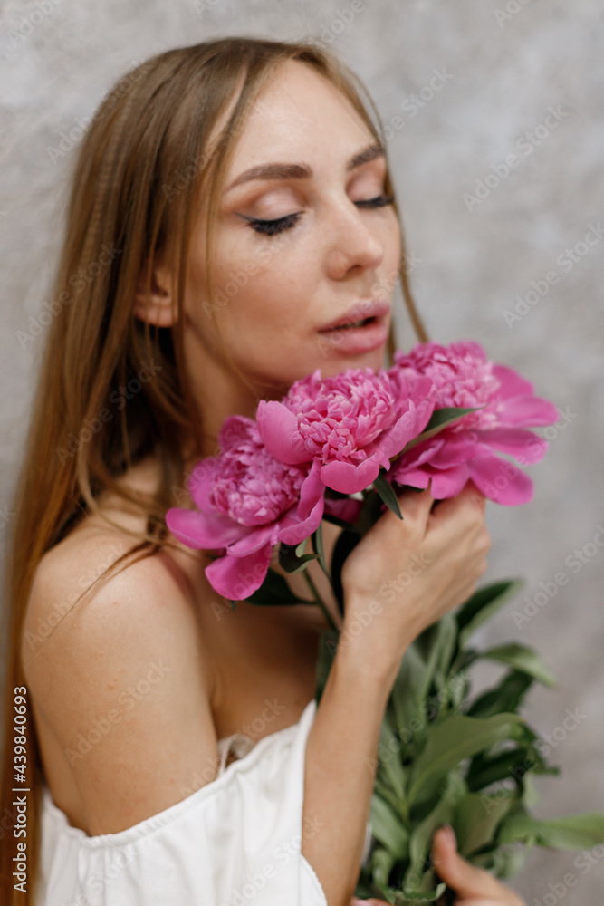 girl with a bouquet of peonies on a gray background close-up