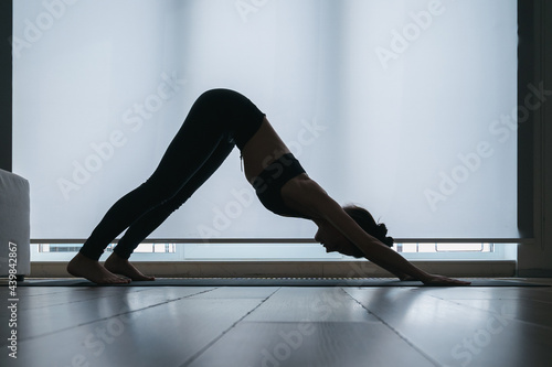 Silhouette of woman practicing yoga at home