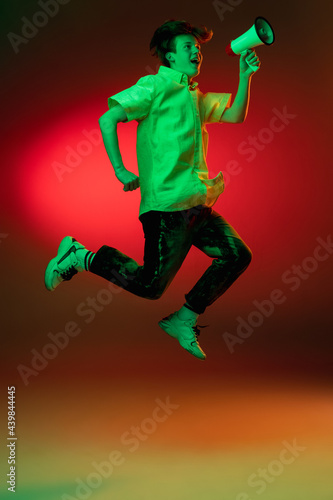 Caucasian young man isolated on blue studio background in neon. Concept of human emotions, facial expression.