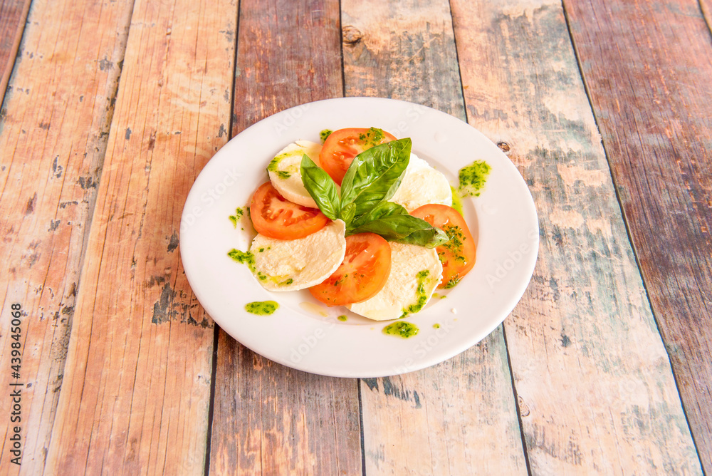 Typical Italian salad with buffalo cheese, tomato, basil, oil with parsley Typical Italian salad with buffalo cheese, tomato, basil, oil with parsley