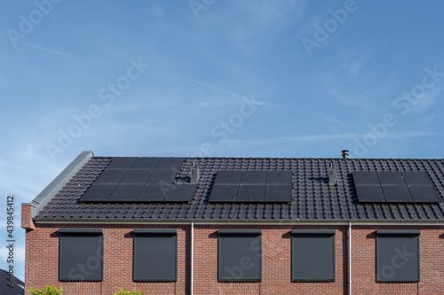 Newly build houses with solar panels attached on the roof against a sunny sky Close up of new building with black solar panels. Zonnepanelen, Zonne energie, Translation: Solar panel, , Sun Energy photo